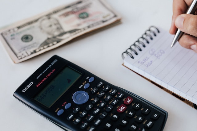 persona haciendo cuentas con una calculadora y libreta