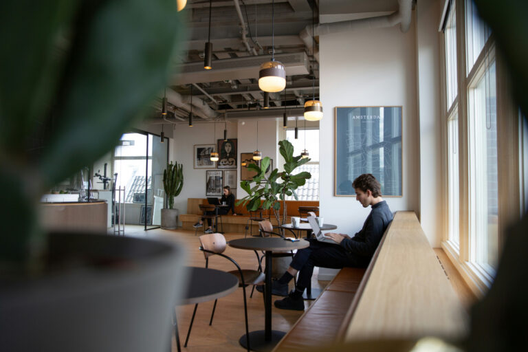 Un chico joven está en un café trabajando en un portátil