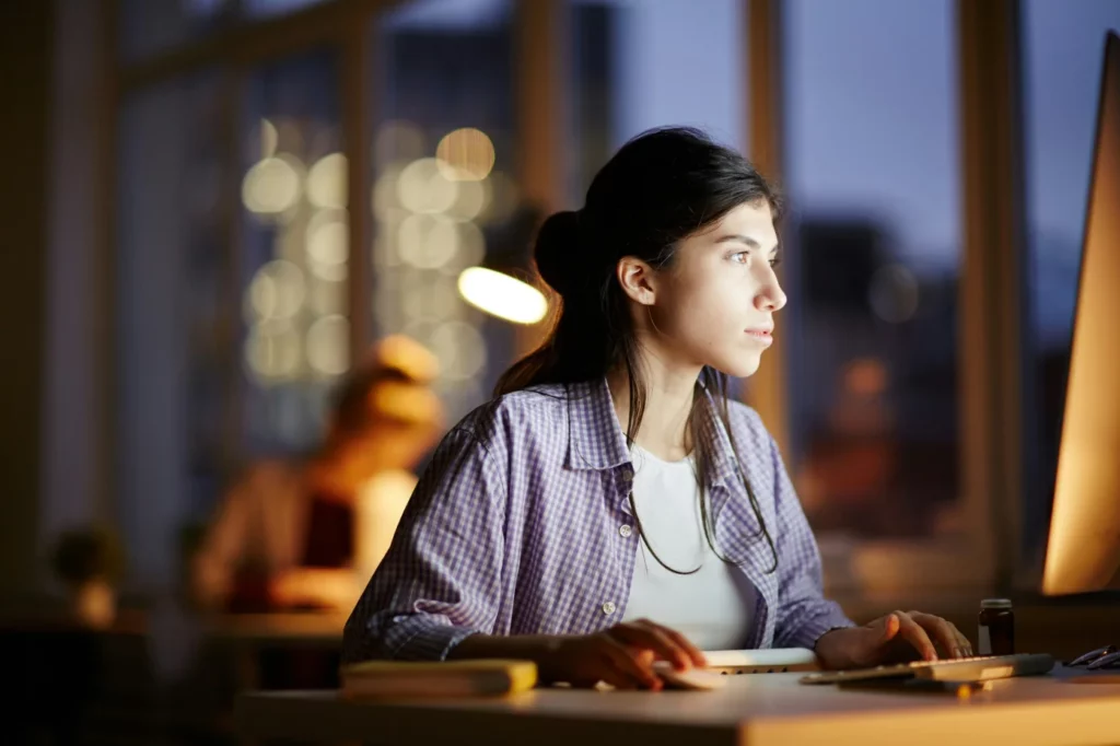 mujer joven usando un ordenador de mesa de noche