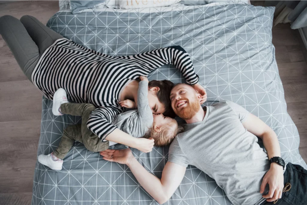 Madre, padre e hijo jugando en la cama.