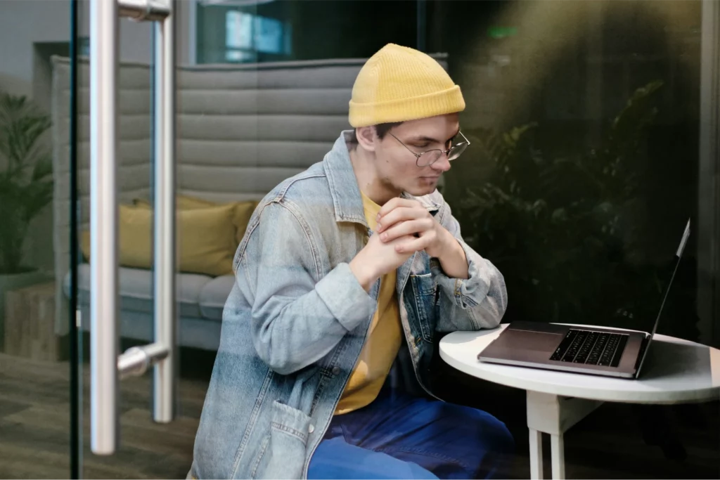 hombre joven con gorro trabajando con un ordenador portátil