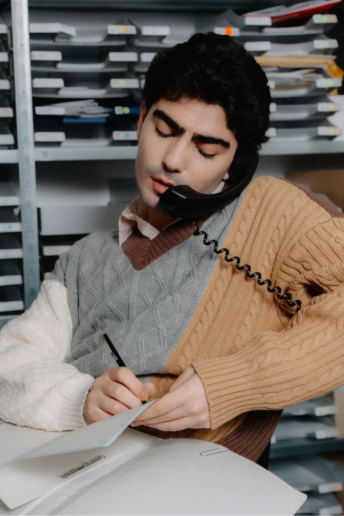 hombre hablando por teléfono mientras escribe en un papel