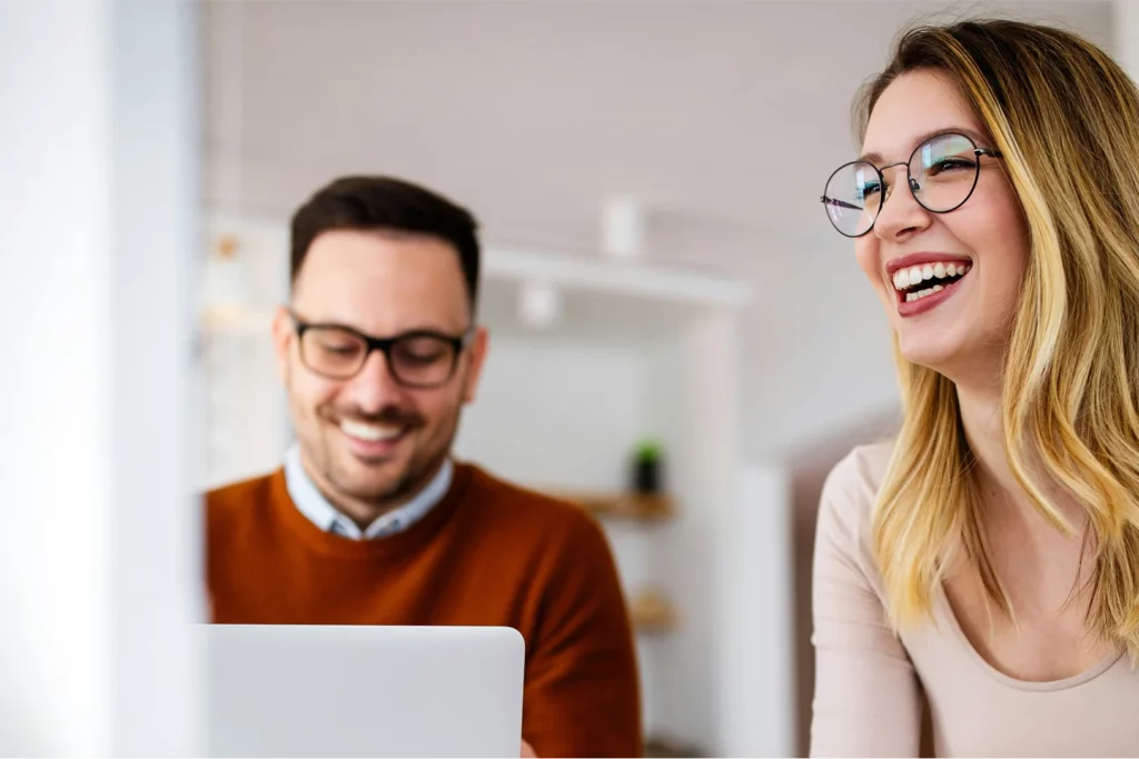 dos personas riendo mirando una pantalla